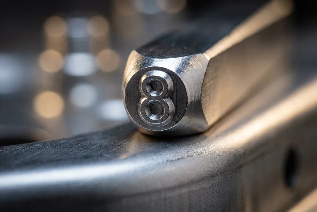 Gros plan macro d'un poinçon en métal pour la frappe à froid sur un châssis, illustrant la précision de la procédure.